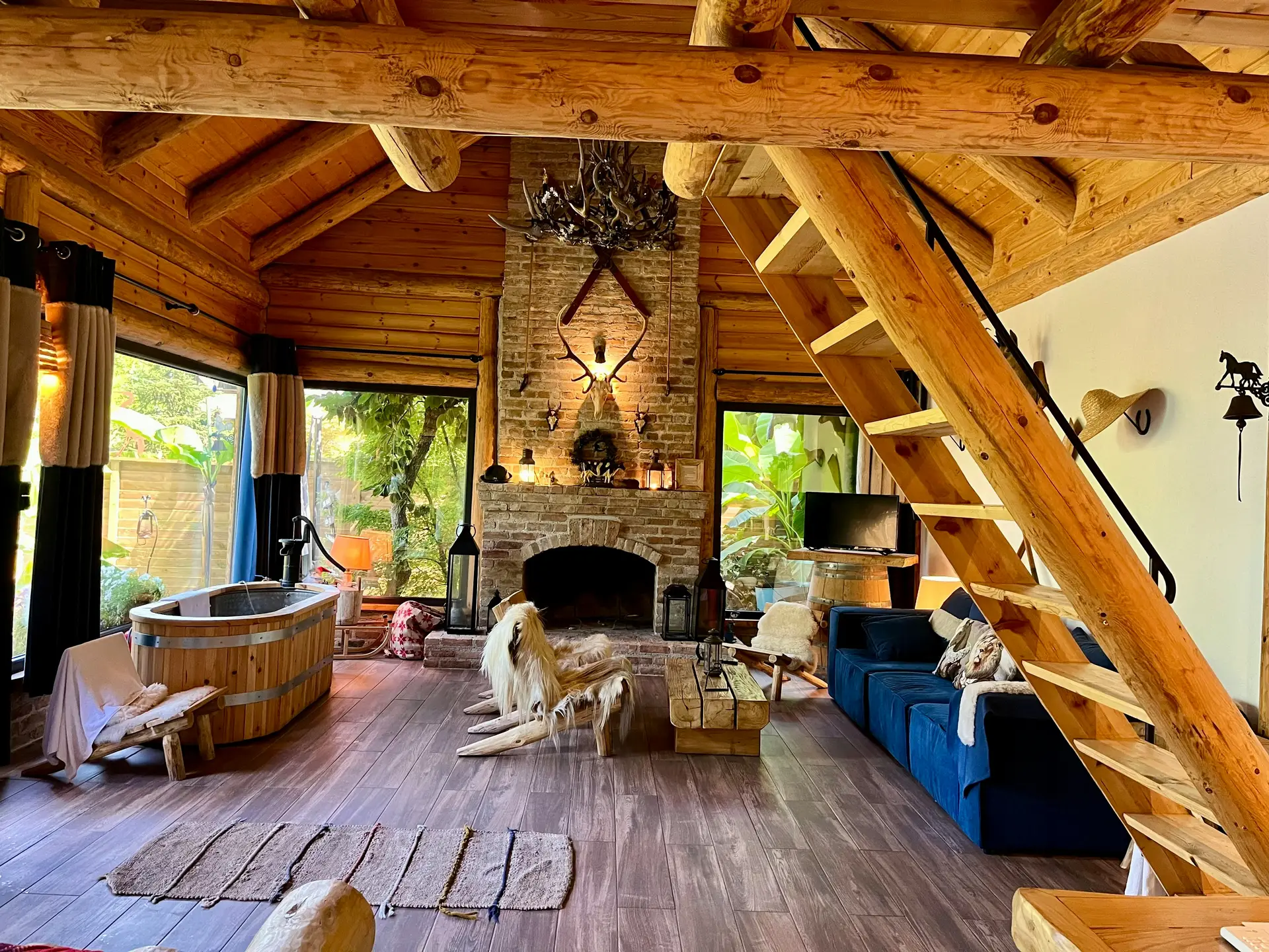 Intérieur chaleureux avec poutres en bois massif, cheminée en pierre naturelle et sol en bois — matériaux naturels durables, Nordéco Interiors